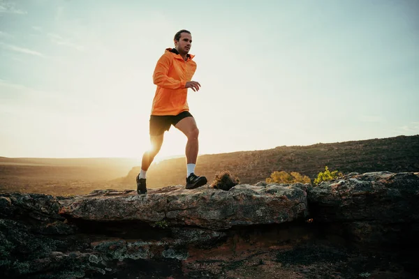 Atleta maschio caucasico che corre nella natura selvaggia godendo esercizio nella foresta durante il tramonto — Foto Stock