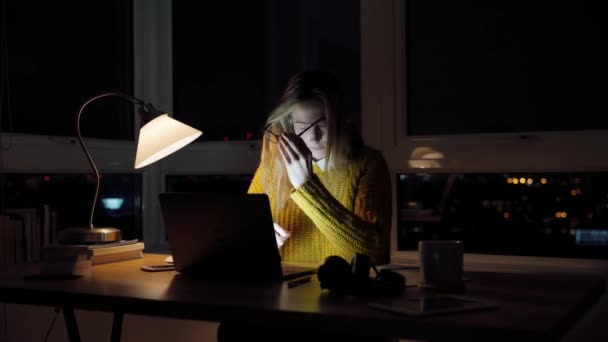 Beyaz bir kız öğrenci gece geç saatlere kadar çalışıyor. Gözlerini ovuşturuyor. Dizüstü bilgisayarda yazı yazıyor. — Stok video