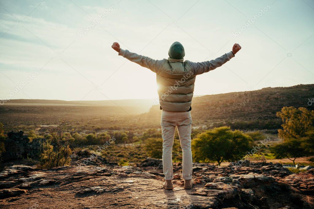 Caucasian male free spirit embracing sunset with arms wide while camping in wilderness