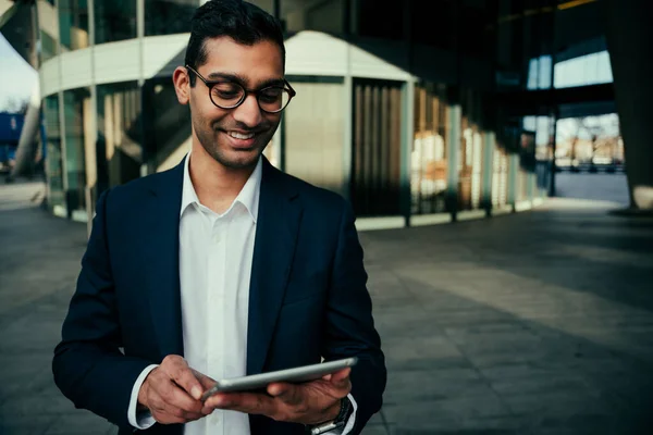 Mixed race businessman smiling typing on digital tablet while working to work office