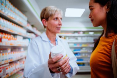 Kafkasyalı kıdemli eczacı, hasta hastaya eczaneden ilaç almasında yardım ediyor.