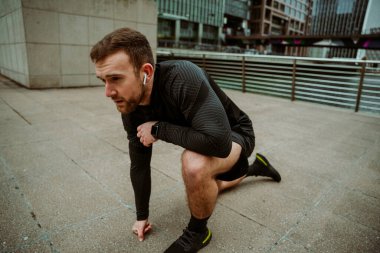 Beyaz erkek sporcu diz çöküp koşmaya hazırlanıyor.