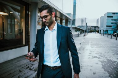 Karışık ırk işadamı iş toplantısından önce akıllı telefondan mesaj atıyor.