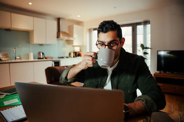 Mieszany biznesmen wyścigowy pracuje w biurze domowym ciesząc się gorącą kawą po długim dniu — Zdjęcie stockowe