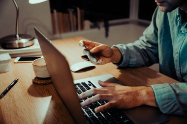 Kafkas erkek iş tasarımcısının dizüstü bilgisayarda çalışıp ödemeyi kartla yapmasını kapatın.