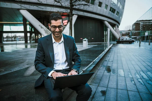 Uomo d'affari misto razza digitando sul computer portatile sorridente dopo una lunga giornata di lavoro — Foto Stock