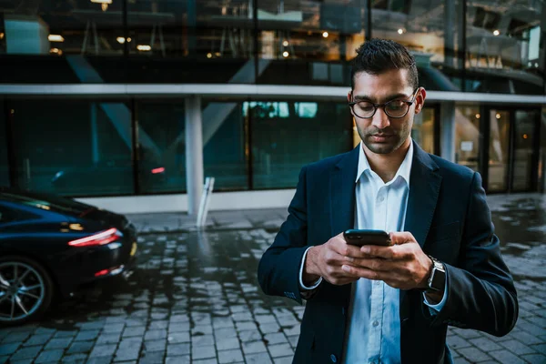 Karışık ırk işadamı. Akıllı telefondan akıllı mesajlar atıyor. Ofisteki iş toplantısına gidiyor.
