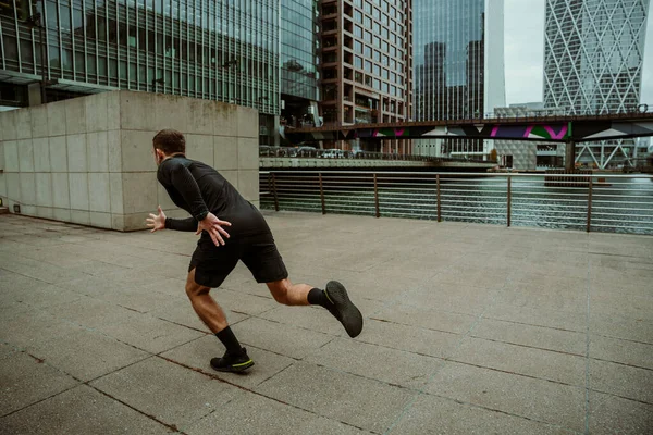 Atleta masculino caucásico corriendo para hacer ejercicio en la ciudad — Foto de Stock