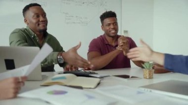 Erkek müdür ve meslektaşları konferans odasında otururken yeni iş ortağıyla el sıkışıyor.