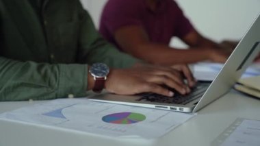 Erkek muhasebeci, konferans odasında oturan dizüstü bilgisayarın hesap tablosuna rakamları kaydediyor.