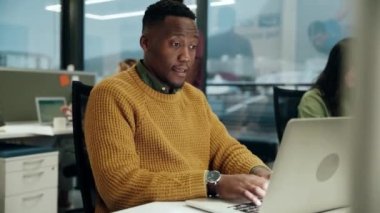 Dizüstü bilgisayarda yazı yazan, ofiste iş yapan kadın meslektaşıyla çalışan etnik bir erkek.