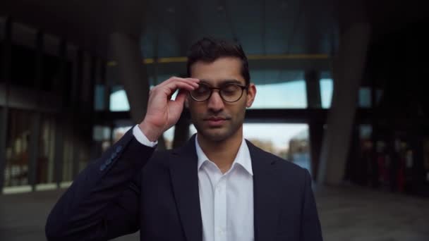 Retrato de homem de negócios de raça mista vestindo óculos olhando para a câmera vestida inteligentemente ao ar livre — Vídeo de Stock