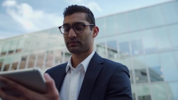 Деловой человек смешанной расы печатает на цифровом планшете улыбаясь стоя вне рабочего офиса — стоковое видео