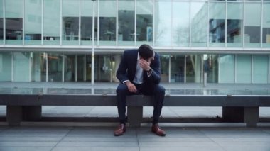 İş yerinin önünde oturan karışık ırk işadamı stresli ve stresli görünüyor.