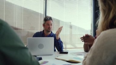 Kafkasyalı erkek yönetici, yeni proje sohbetleri için iş arkadaşlarına rehberlik ediyor.
