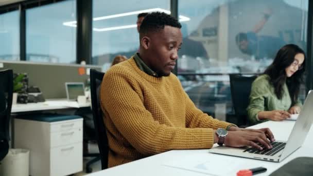 Афроамериканец, работающий над ноутбуком, печатает быстрые письма, работая с коллегами в офисе — стоковое видео