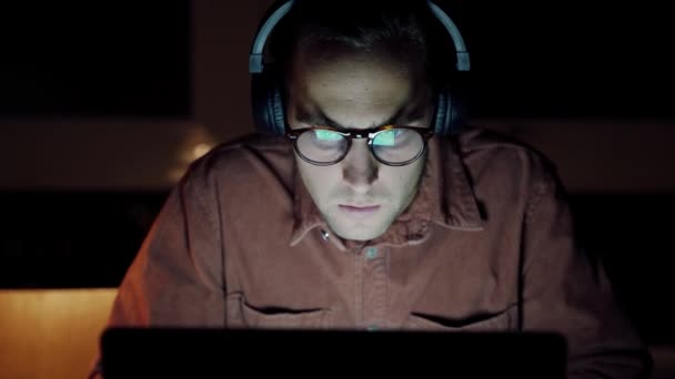 用笔记本电脑上的耳机对收听音乐的高加索男性自由职业者进行近距离观察 — 图库视频影像