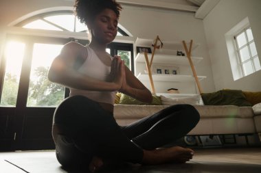 Yoga yaparken nefes alma teknikleri uygulayan genç bir bayan dinlenme odasında oturuyor. 