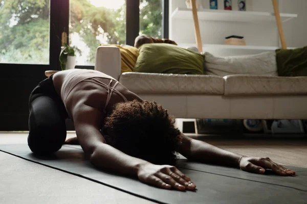 Vrouwelijke yogi die kinderen vasthoudt stellen zich uitrekkend op yoga mat in moderne lounge — Stockfoto