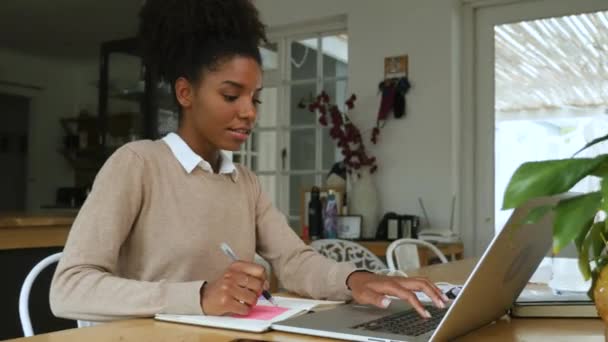 Fiatal vegyes fajú nő afro dolgozik otthonról előtt laptop — Stock videók