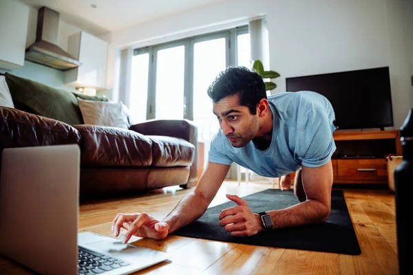 Karışık ırk erkek sporcusu. Ev ödevi olarak dizüstü bilgisayar kullanıyor. 