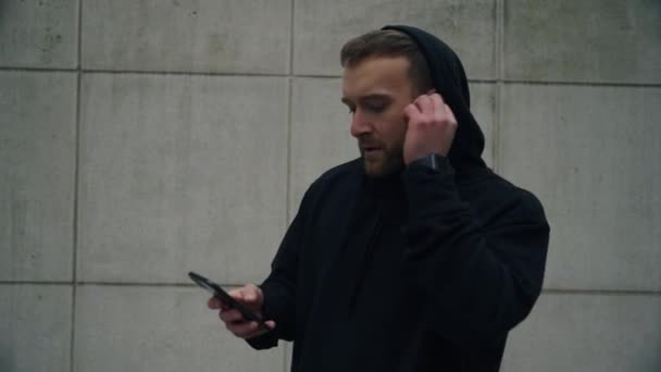 Atlet caucazian de sex masculin tastând pe smartphone ascultând muzică cu căști — Videoclip de stoc