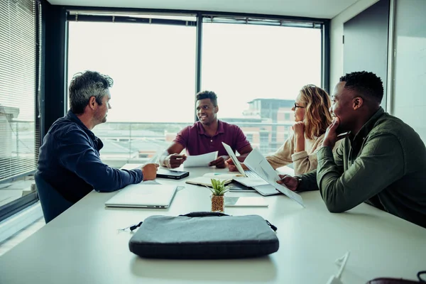 Caucasian male boss briefing team on goals for start up of new business sitting around table in conference room — стоковое фото