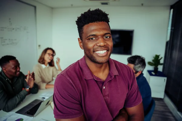 Genç melez erkek portresi salonda meslektaşlarının önünde sunumdan önce özgüvenle gülümsüyor.