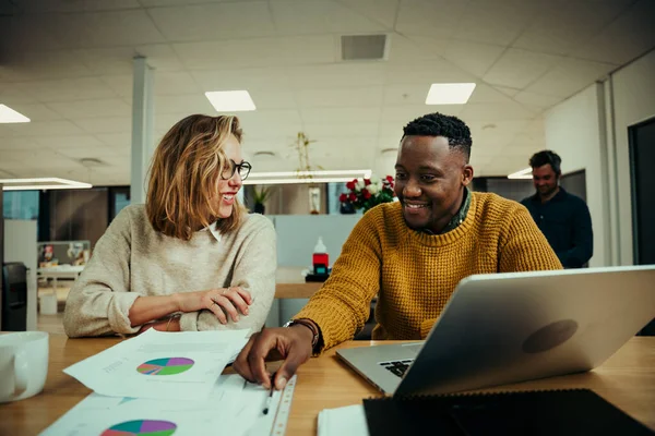 Genç bir kadın iş adamıyla belgeleri tartışıyor. Dizüstü bilgisayarla araştırma yapıyor. Toplantı aralarında ofisin giriş salonunda çalışıyor.