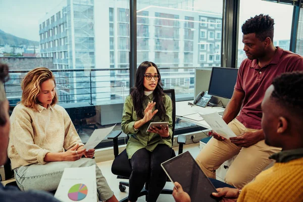 Çeşitli genç tasarımcılardan oluşan bir grup, yeni projenin özetini tartışan takım toplantısında beyin fırtınası yapıyor.