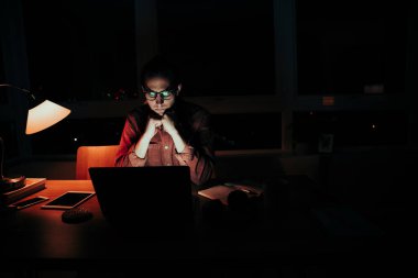 Beyaz erkek, bileklerine yaslanıp laptopta makaleler okuyarak ofis masasında oturuyor.