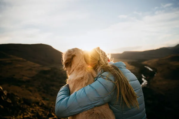 Caucásico adolescente vinculación con oro cachorro sentado en la cima de la montaña viendo vibrante puesta de sol —  Fotos de Stock