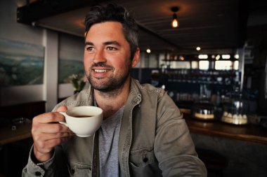 Yakışıklı erkek müşteri moda kafede sıcak kahve içiyor. 