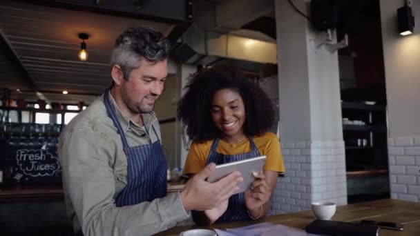 Ober en serveerster beheren nieuwe online menu op digitale tablet nippen koffie in funky cafe. — Stockvideo