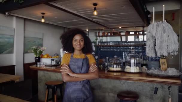 Schöne Kellnerin steht mit überkreuzten Armen in flippigem Café — Stockvideo