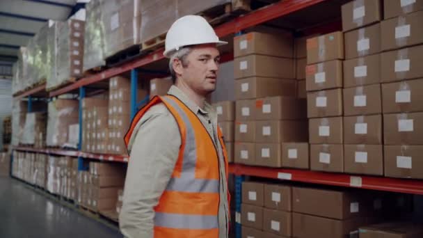 Inteligente hombre de negocios que trabaja en fábrica vistiendo uniforme sonriente de pie cruz armada buscando profesional en el almacén — Vídeos de Stock