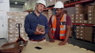 Melez ırk meslektaşları depoda duran tablete bakarak iş fikirlerini tartışıyor.