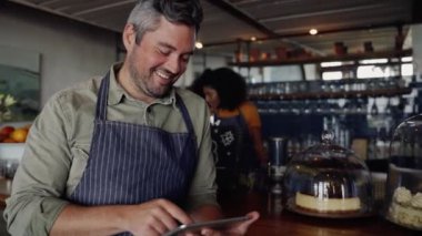 Moda kafenin tezgahına yaslanırken önlük takan yakışıklı bir erkek..