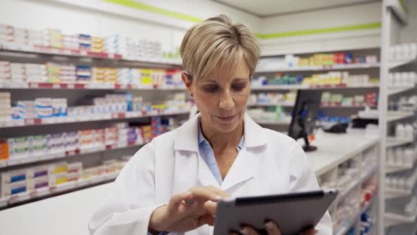 Усміхнена жінка-фармацевтка прокрутка на цифровому планшеті керівництво інтерном в аптеці — стокове відео