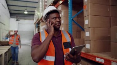 Karışık ırk işadamı iş arkadaşlarıyla konuşuyor. Fabrikada yürürken dijital tablet üzerinde kontrol listesi hazırlıyorlar. 