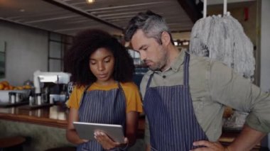 Garson ve garson son moda kafede dikilirken dijital tablette online menü üzerinde çalışmaya çalışıyor.