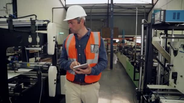 Чоловічий менеджер перевіряє машини на заводі під час прокрутки через контрольний список ходьби на складі — стокове відео