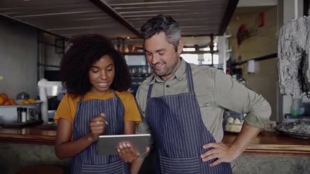 男性と女性のウエイトレスはファンキーカフェでデジタルタブレットを使用して注文を記録 — ストック動画