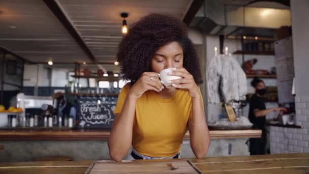 Piękna mieszana rasa nastolatek po prostu picie gorącej kawy w stylowej kawiarni — Wideo stockowe