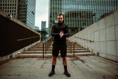 Beyaz erkek sporcu fitness eğitimine hazırlanıyor. Şehir merkezinde duruyor.