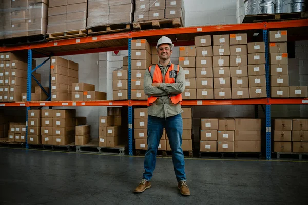 Handsome caucasian worker standing with pride in front of packaged parcels in warehouse — Stock Photo, Image