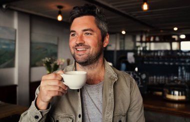 Süslü bir kafede sıcak kahve içerken gülümseyen yakışıklı beyaz adam.. 