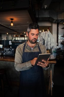 Erkek garson, modaya uygun kafede dijital tablet menüsünü karıştırıyor. 