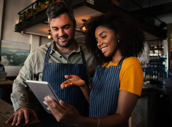 Sorridenti colleghi di sesso maschile e femminile discutono i piani mentre guardando un tablet in piedi in caffetteria. — Foto Stock