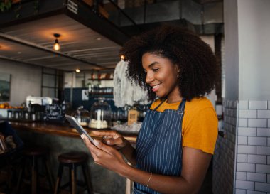 Güzel Afrikalı Amerikalı kadın tablet üzerinde kayıyor. Kafe duvarına yaslanırken. 